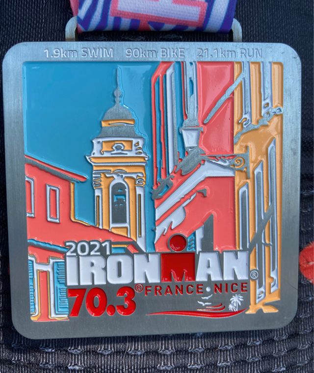 Medaille vom Ironman France Nice 2021 mit buntem Design, zeigt Stadtansicht